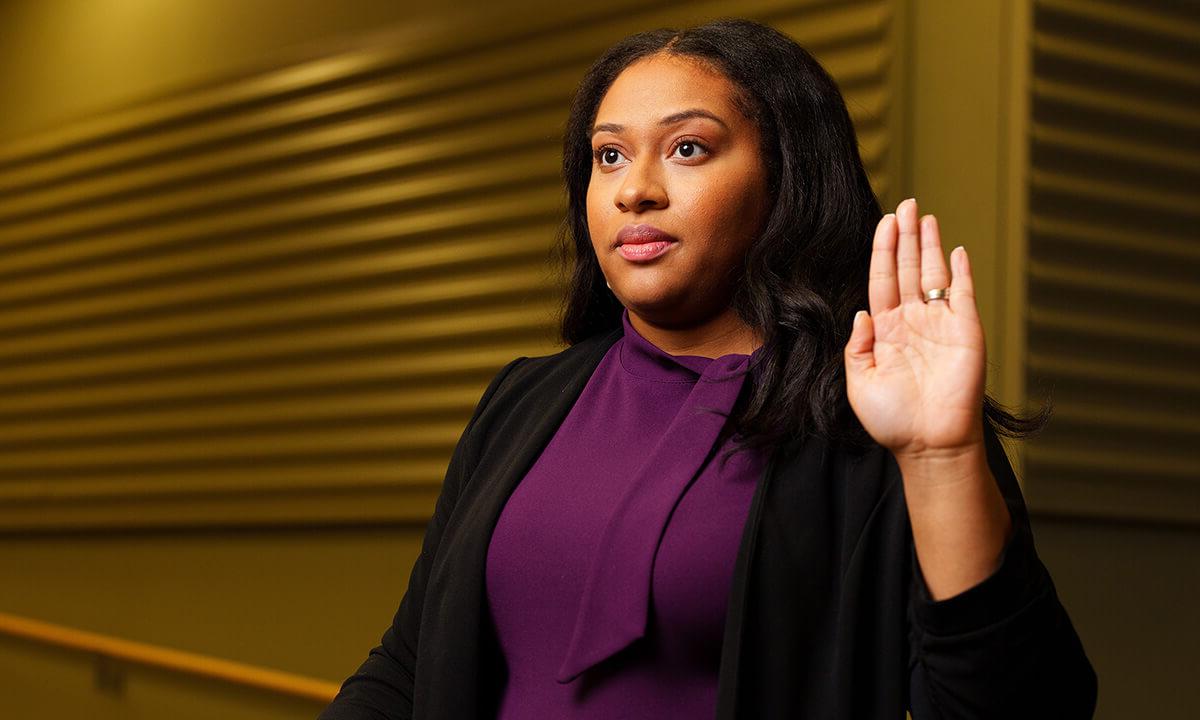 A woman raises her hand as if taking an oath.